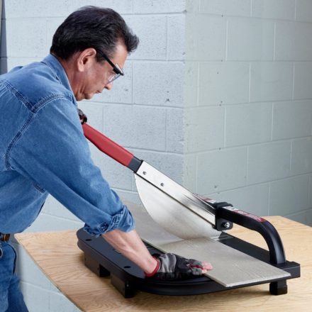 Construction worker in a jean jacket cutting a section of Fiber Cement board with a Malco FCC7 guillotine