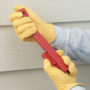 Construction worker holding a red Malco FCFG tool with fiber cement siding in the background