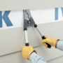 Construction worker using Malco's SNC to cut a nail under a fiber cement board