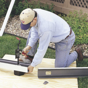A male using the Gutter Outlet Punch Tool by Malco.