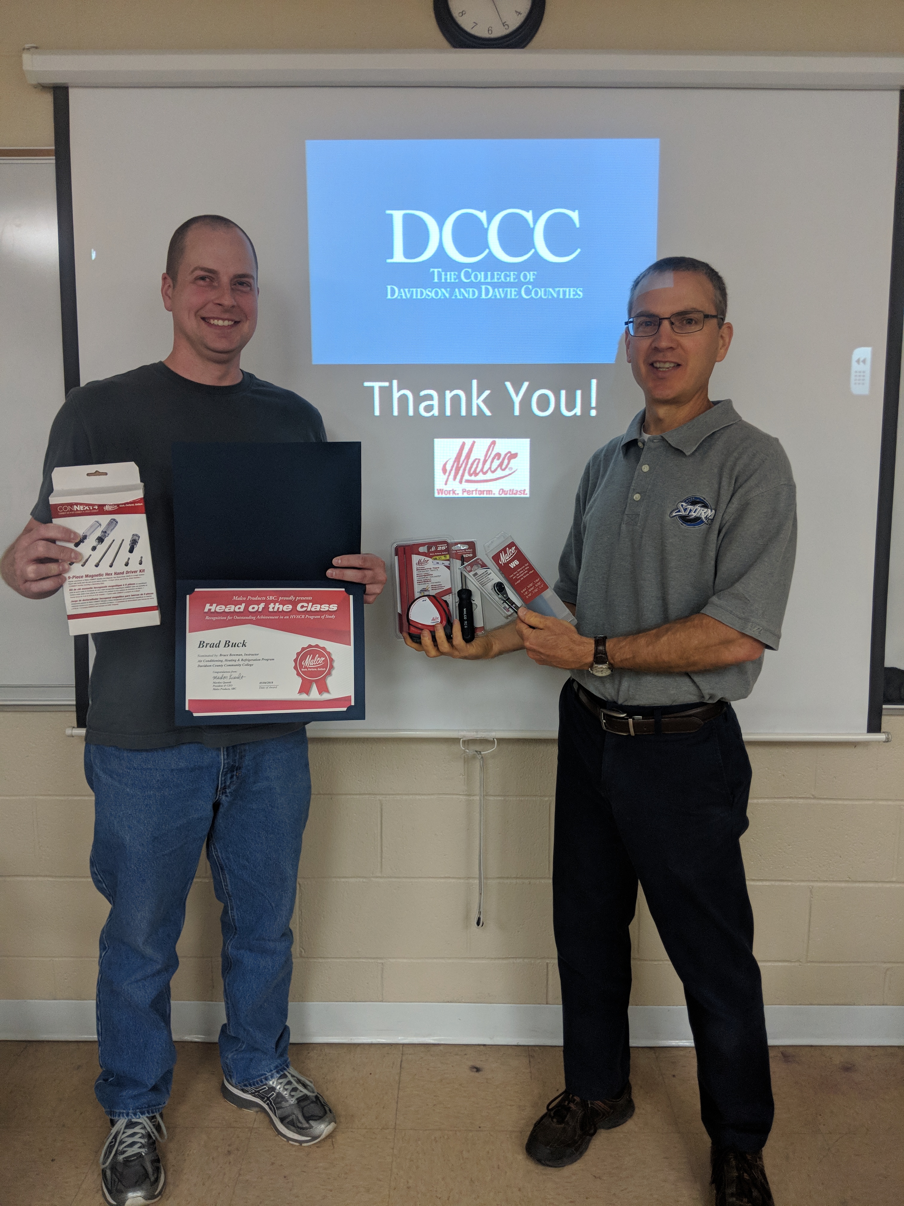 Teacher and student holding Malco tools and a certificate of head of class