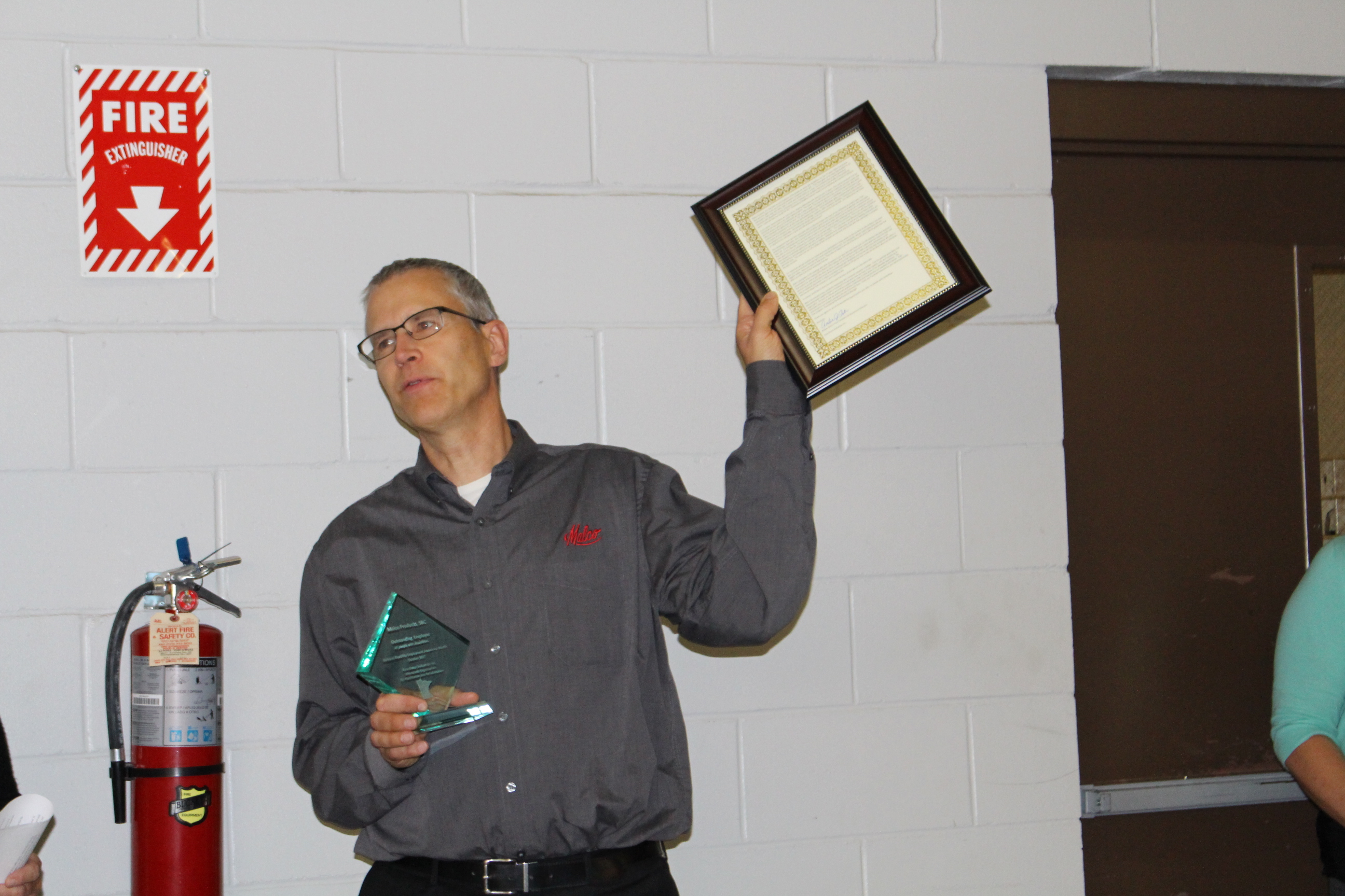 Malco President and CEO, Mardon Quandt, holds high the framed Disability Employer award nomination letter written by Functional Industries’ Amber Oster