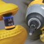Worker holding a one of Malco's C-Rhex Magnetic Driver in one hand and in the other hand holding a power drill