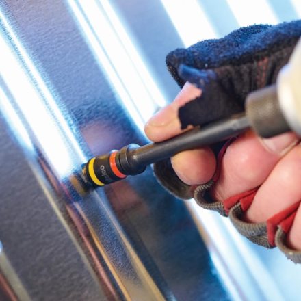 A screw being fastened with a Malco 7 and 8 MM CRHEX in a piece of roofing