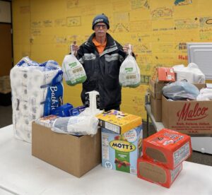 Malco employee volunteering, and holding a bag of groceries.