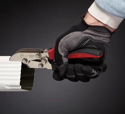 Worker with gloved hands using Malco's C4R Gutter Tool to crimp a white downspout