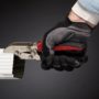 Worker with gloved hands using Malco's C4R Gutter Tool to crimp a white downspout