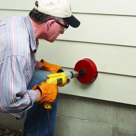 Man using Malco Hole Saw to cut through Hardie Siding