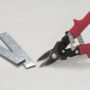 Malco's Bulldog Aviation Snips next to a cut piece of sheet metal