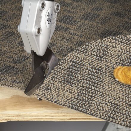 A worker cutting a corner of rug fabric using Malco's TSV1 TurboShear